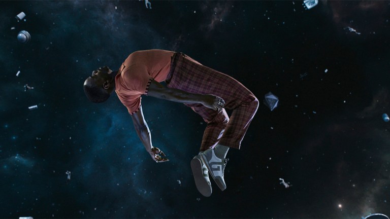 Ncuti Gatwa as the Fifteenth Doctor in tartan trousers and an orange top unconscious and floating in space