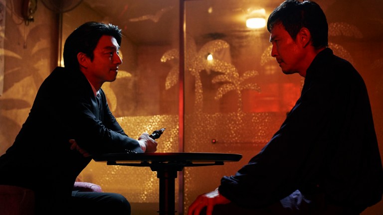 Seong Gi-hun (Lee Jung-jae) sits in front of a Squid Game recruiter in a shadowy room in Squid Game season 2.